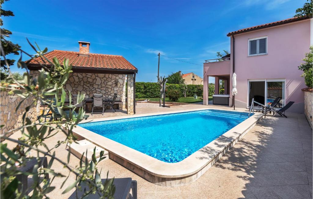 a swimming pool in front of a house at Amazing Home In Pula With Wifi, Jacuzzi And Outdoor Swimming Pool in Pula