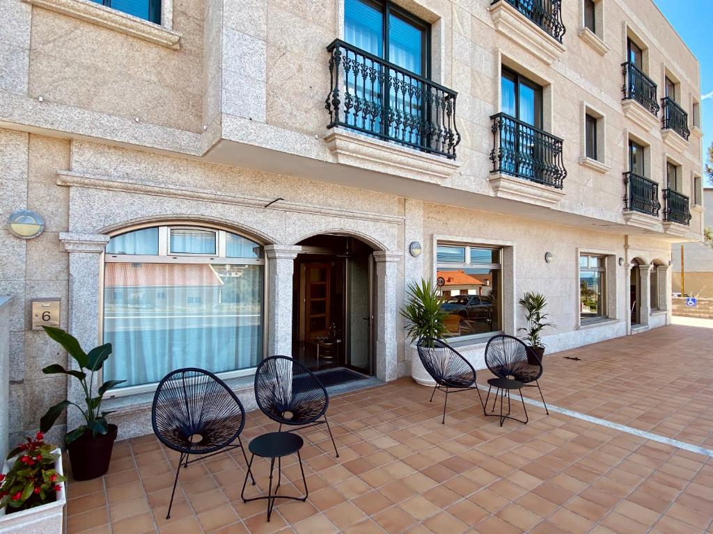 - un ensemble de chaises assises sur une terrasse en face d'un bâtiment dans l'établissement Duerming Areas Playa Hotel, à Sanxenxo