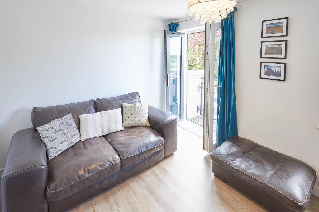 sala de estar con sofá de cuero marrón y taburete en Host & Stay - Castle View en Durham