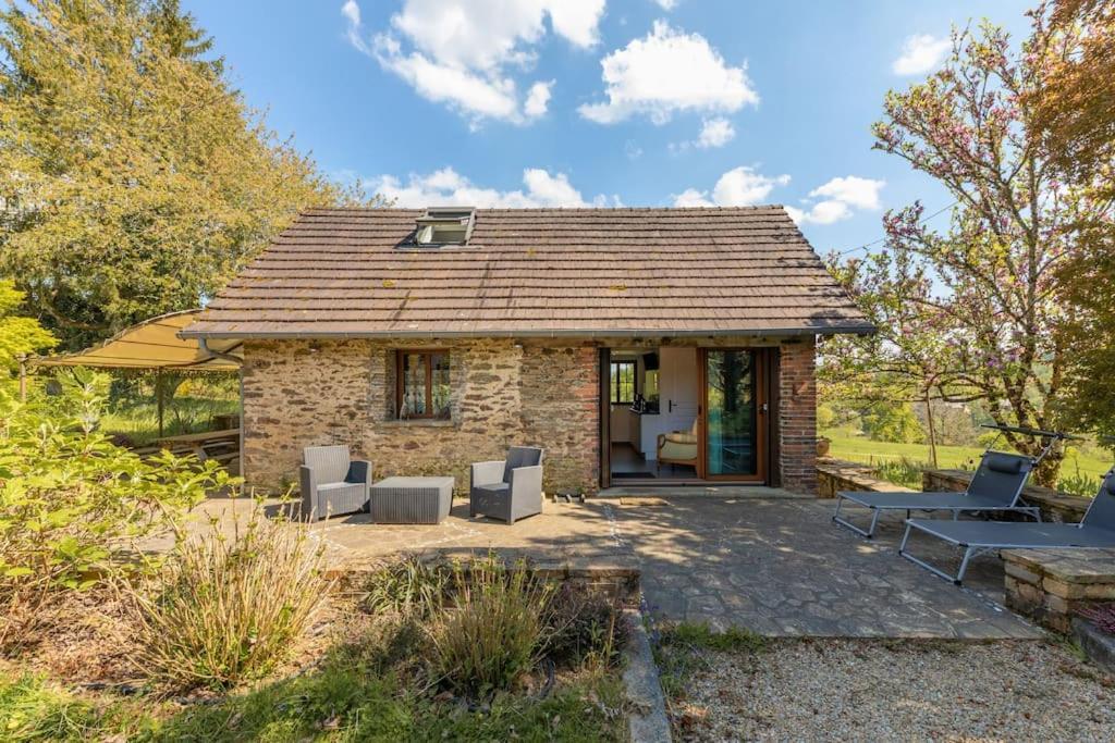 uma pequena casa de pedra com cadeiras e um pátio em Gîte La Bergerie em Ségur-le-Château