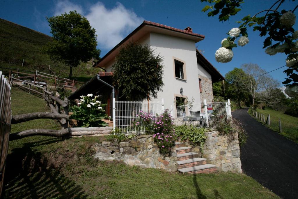una casa blanca con una valla y algunas flores en Casa Campu 1, en Pandavenes