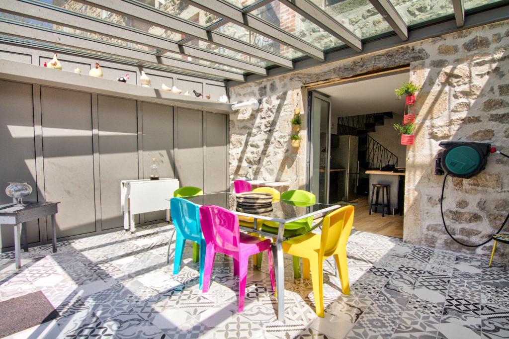 a patio with a table and colorful chairs at Le Pop in Saint-Julien-Chapteuil