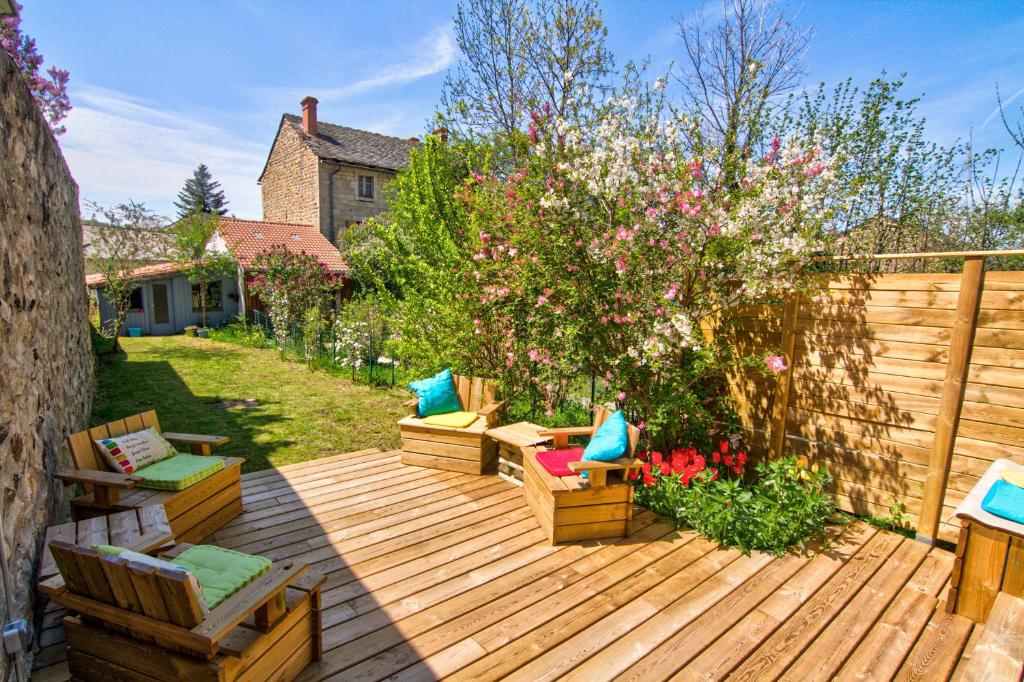a wooden deck with chairs and flowers in a yard at Le Pop in Saint-Julien-Chapteuil