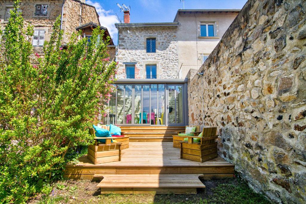 ein Haus mit einer Steinmauer und einer Holzterrasse in der Unterkunft Le Pop in Saint-Julien-Chapteuil