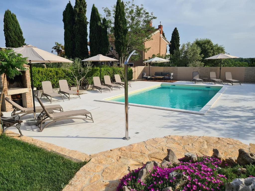 een zwembad met stoelen en parasols in een tuin bij Apartmani Gržinić in Rovinj