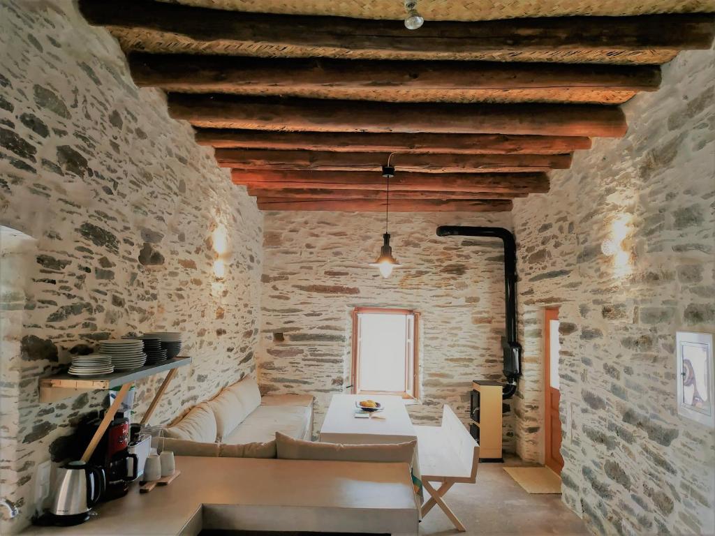 a living room with a white couch and a stone wall at Konaki Hikers Lodge by Andros Routes in Andros
