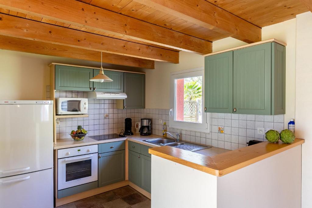 a kitchen with green cabinets and a white refrigerator at Ty Lann in Telgruc-sur-Mer