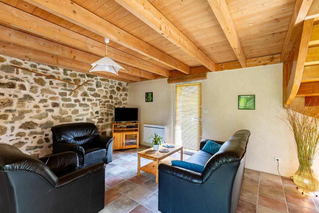 a living room with leather furniture and a stone wall at Ty Lann in Telgruc-sur-Mer