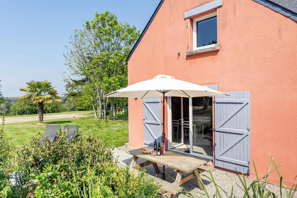 einen Picknicktisch mit einem Regenschirm neben einem Gebäude in der Unterkunft Ty Tevenn in Telgruc-sur-Mer