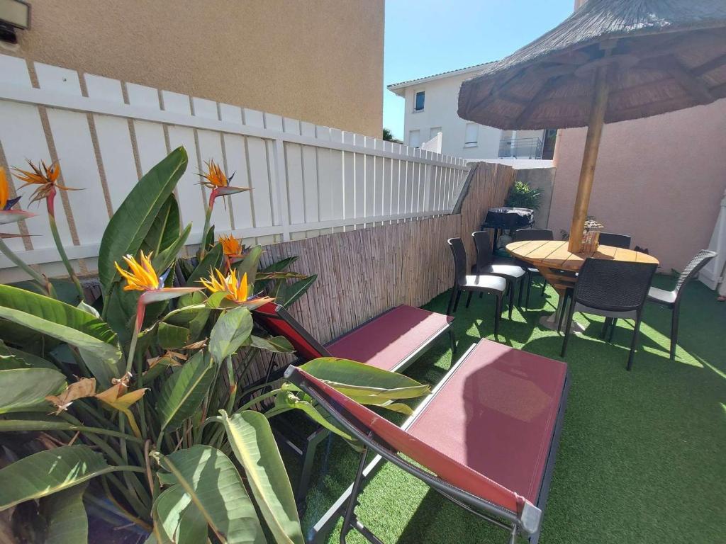 un patio avec des chaises, une table et un parasol dans l'établissement Maison Duplex 3 Pièces, Terrasse, Parking, Plage à Proximité, Idéal Famille - 6 Pers. - FR-1-326-658, à Marseillan