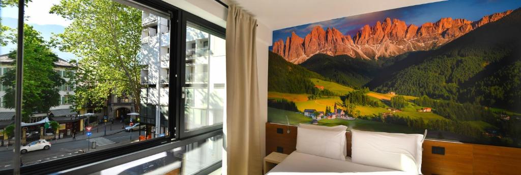 Habitación con ventana y mural de montaña. en YUGOGO PELLICO 8 Trento Centro, en Trento
