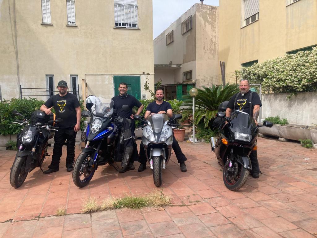 a group of men on motorcycles parked in front of a building at Hotel L'Ancora in La Caletta