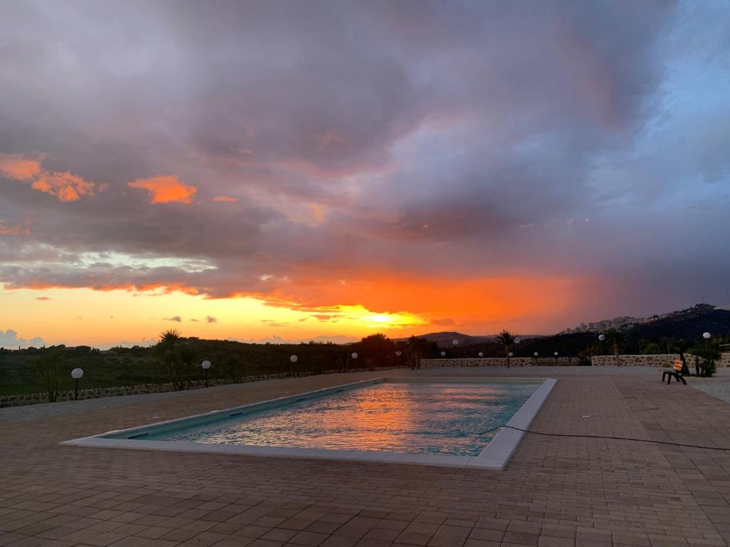 a sunset over a swimming pool with the sun setting at Monte Mosè in Agrigento