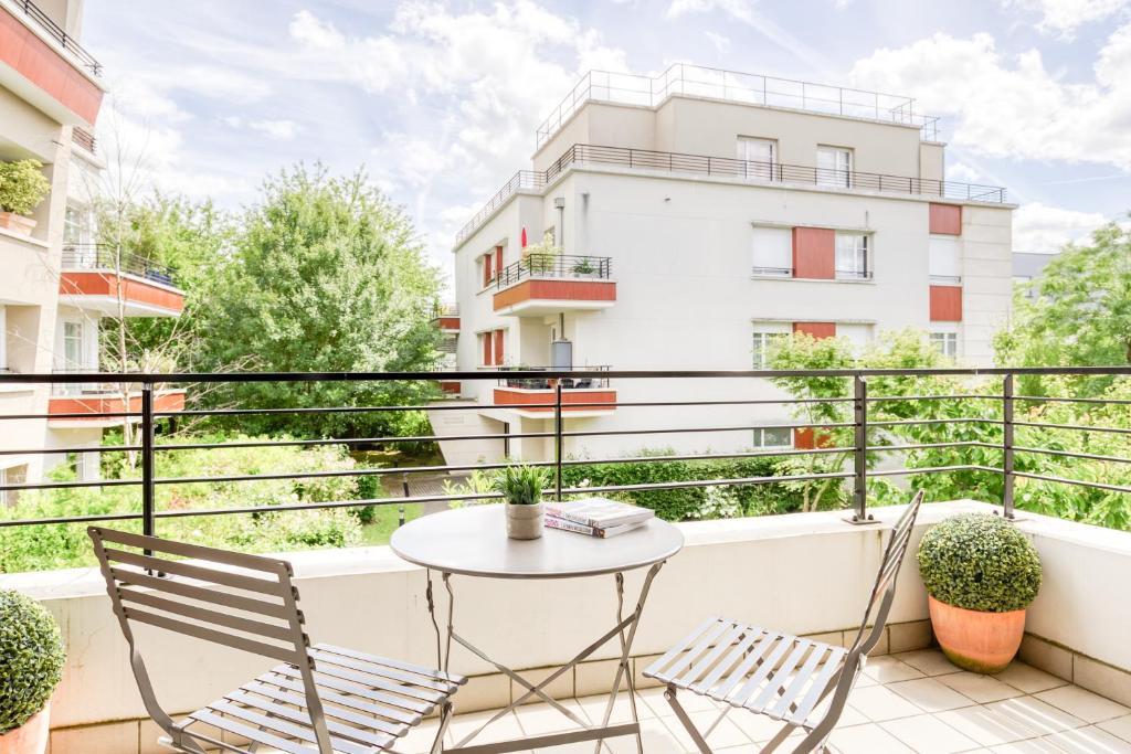 een balkon met een tafel en stoelen en een gebouw bij Cosy appartement Proche Disneyland Paris in Montévrain
