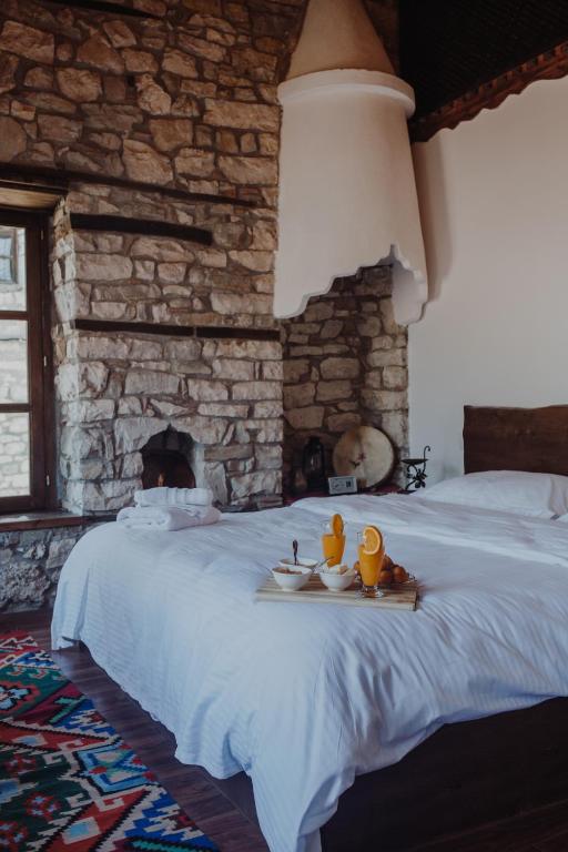 a bedroom with a large white bed with a stone wall at Tradita e Beratit in Berat