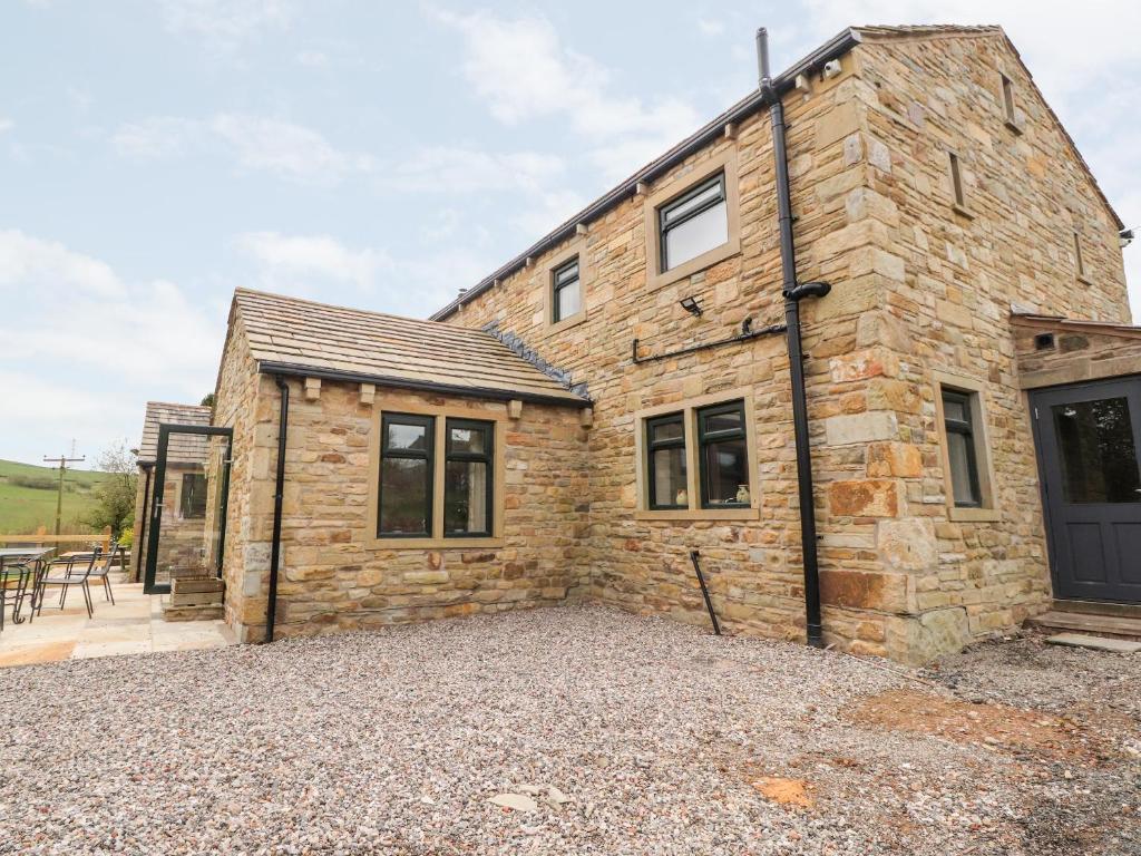a stone house with a gravel driveway in front of it at Batty Hole Farm in Burnley