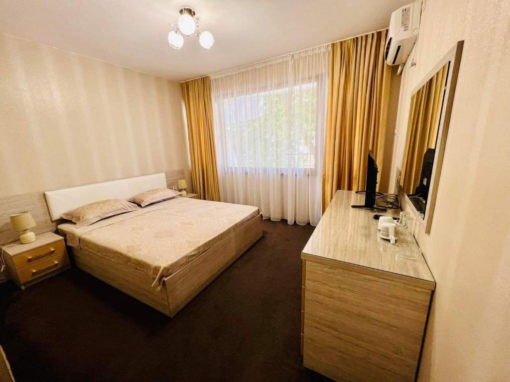 a bedroom with a bed and a desk with a television at Джорджия in Kiten