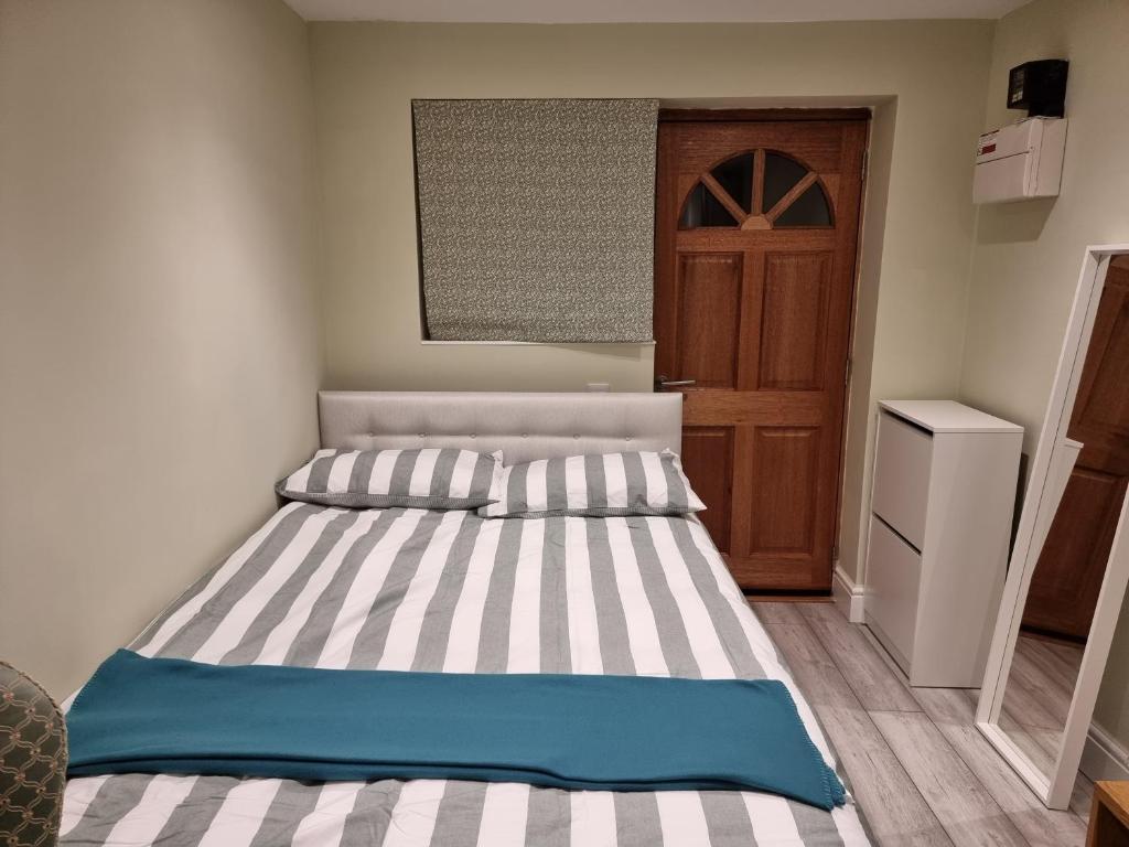 a bedroom with a bed with striped sheets and a door at Studio room in Oxford