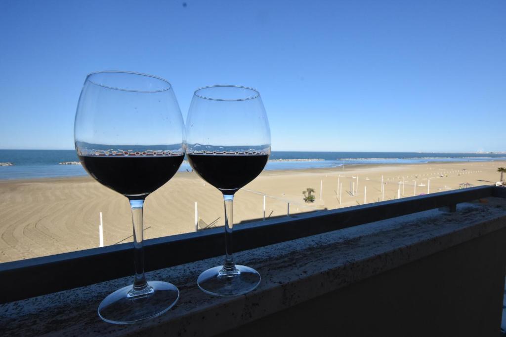 里米尼的住宿－超級酒店，两杯葡萄酒坐在俯瞰海滩的帐篷上
