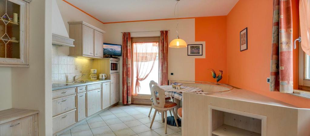een keuken met oranje muren en een tafel en stoelen bij Elisa Bait Giobbe in Livigno