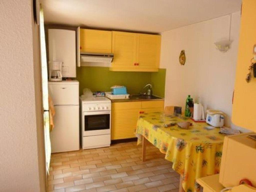 une cuisine avec une table et un réfrigérateur blanc dans l'établissement Villa Mitoyenne Calme avec Piscine, Jardin et Parking Privé, à Proximité de la Plage et Commerces - FR-1-607-33, au Cap d'Agde