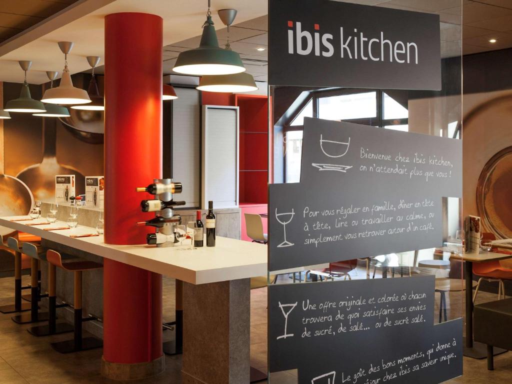 a restaurant with a counter with a bar with chairs at ibis München Parkstadt Schwabing in Munich