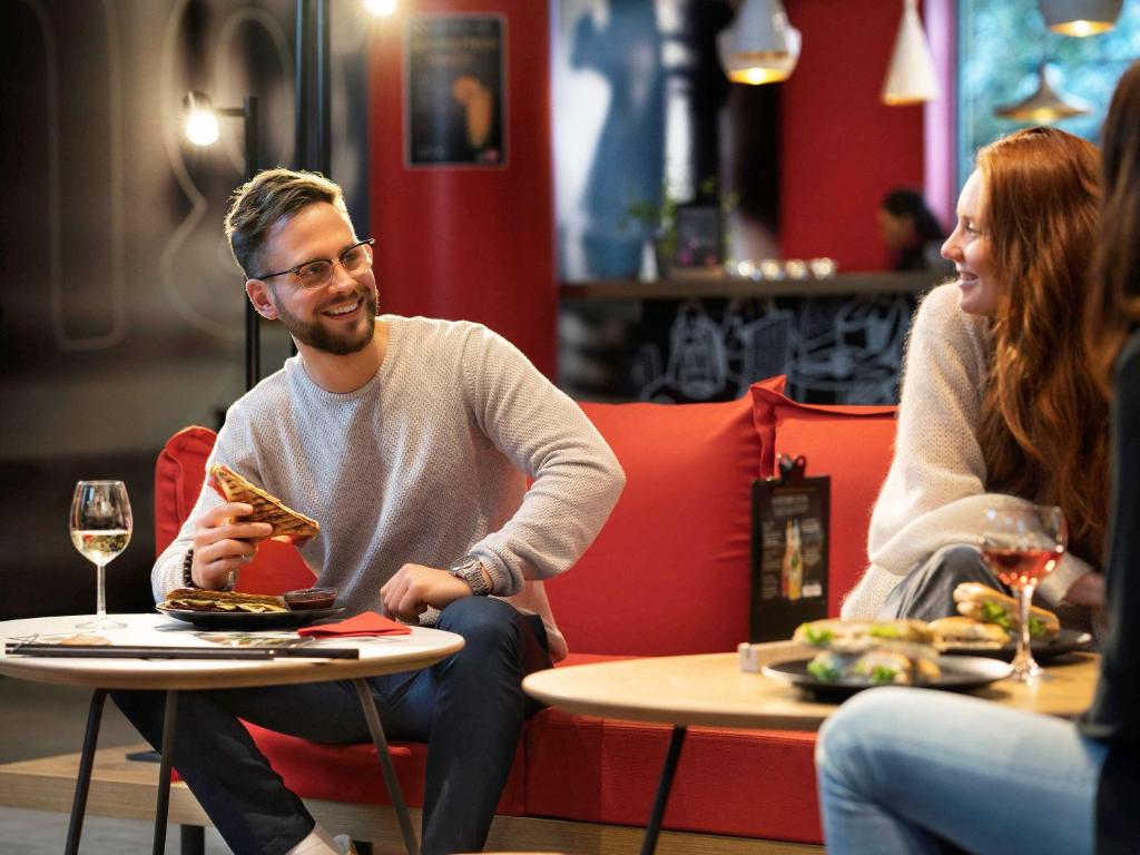 a man and woman sitting at a table eating food at ibis München Parkstadt Schwabing in Munich