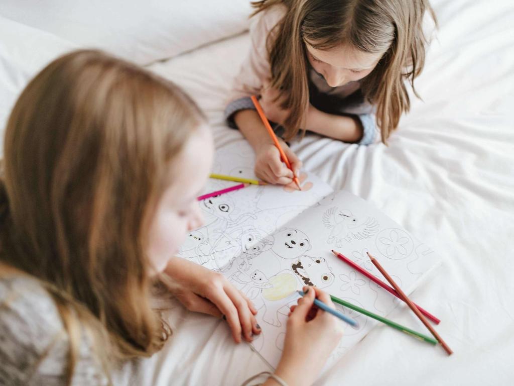 two little girls laying on a bed with drawings at ibis München Parkstadt Schwabing in Munich