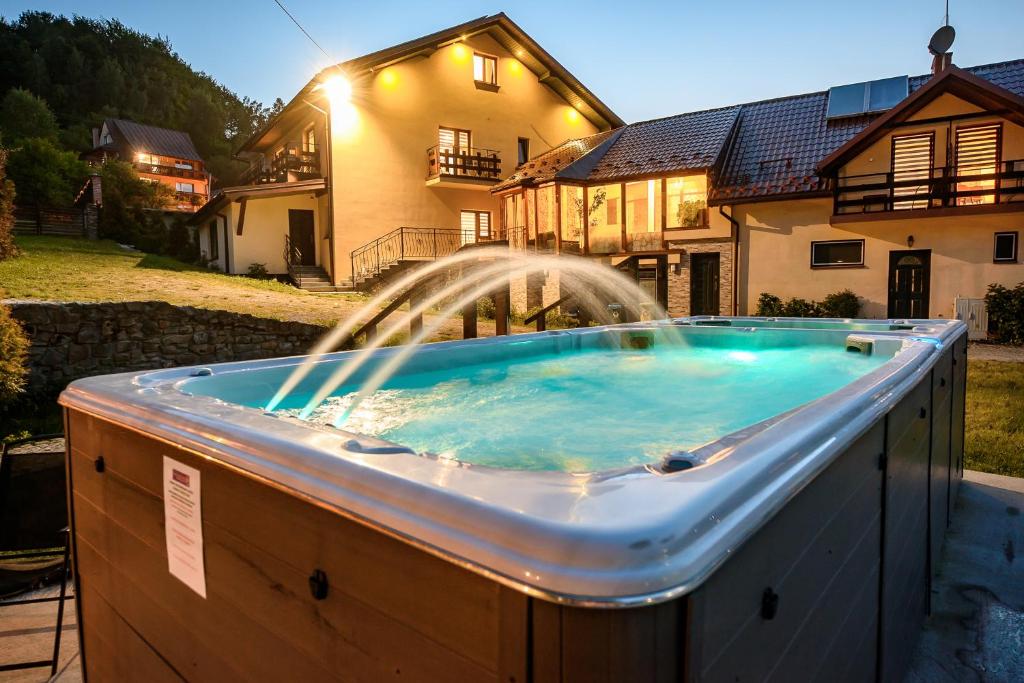 a hot tub with a fountain in front of a house at Osada nad Słotwinką in Krynica Zdrój