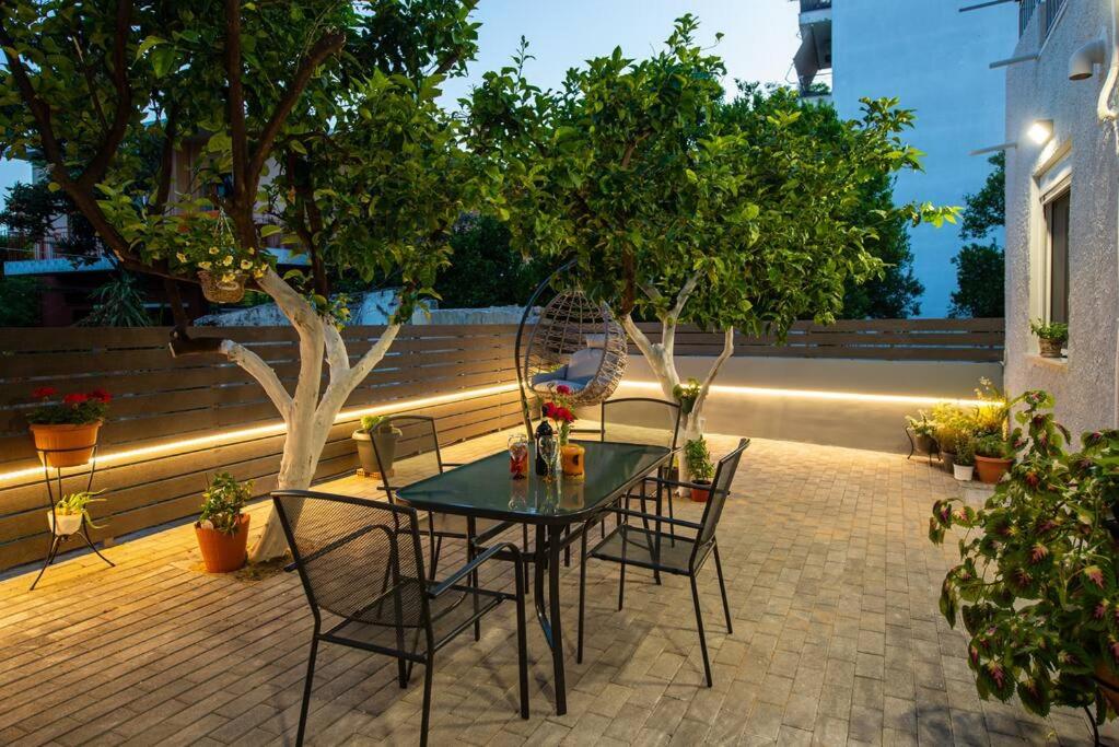 a table and chairs on a patio with trees at Lemon Garden Stylish private apartment in Kalamata