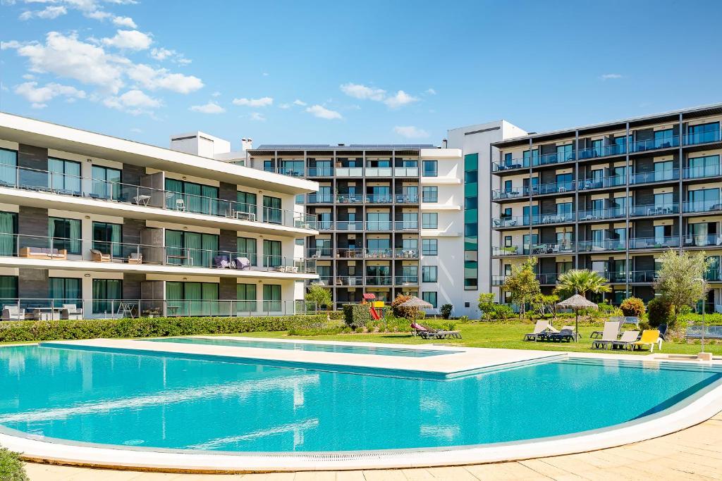 une piscine en face d'un bâtiment dans l'établissement Apartment Residence Golf , with garden and pool, à Quarteira