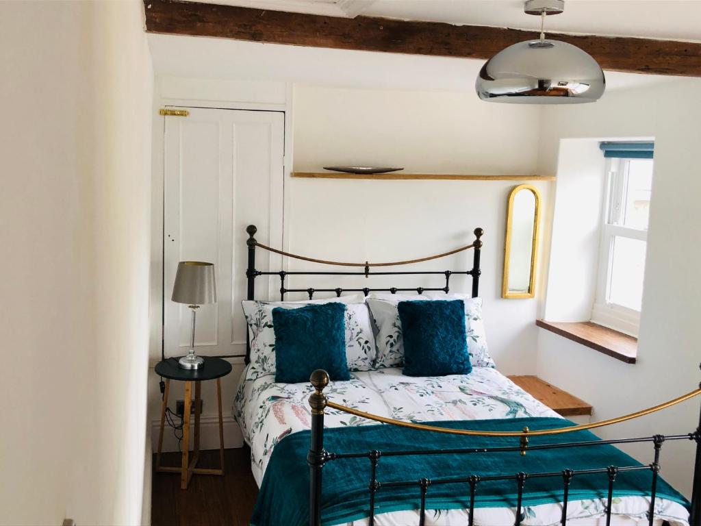 a bedroom with a bed with blue pillows at Mount Cottage in Newcastle Emlyn