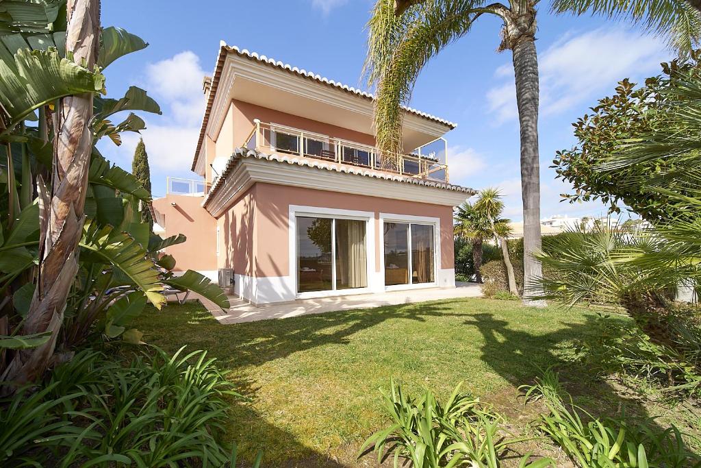 a pink house with palm trees in a yard at 812 Quinta Marina in Lagos