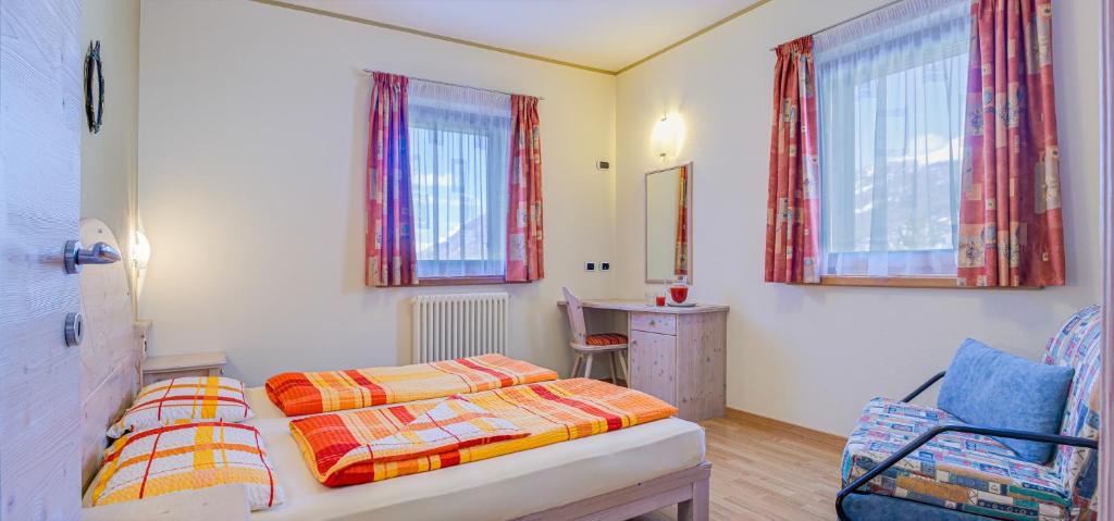 a bedroom with two beds and a chair and windows at Alice Bait Giobbe in Livigno