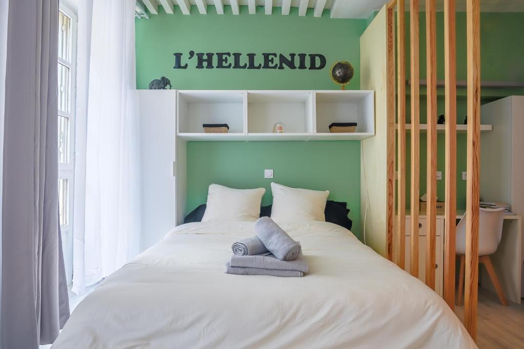 a bedroom with a white bed with a green wall at L'HélleNid : Studio CONFORT Riom Centre in Riom