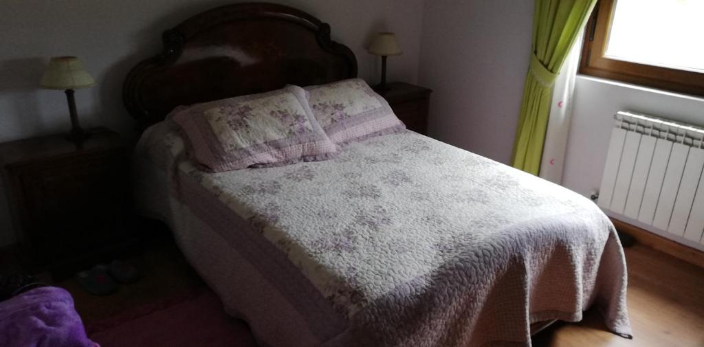 a bedroom with a bed with a blanket and a window at Casa Herbellas in Cedeira