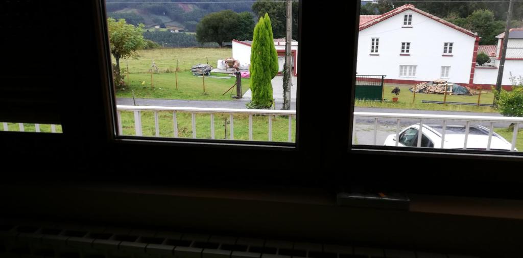 a window with a view of a field and a house at Casa Herbellas in Cedeira