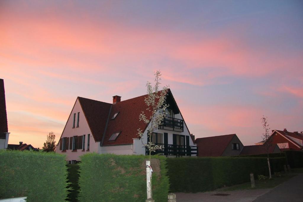 ein weißes Haus mit rotem Dach unter Sonnenuntergang in der Unterkunft Bilderdijklaan 8 Château Petit Sable in De Haan