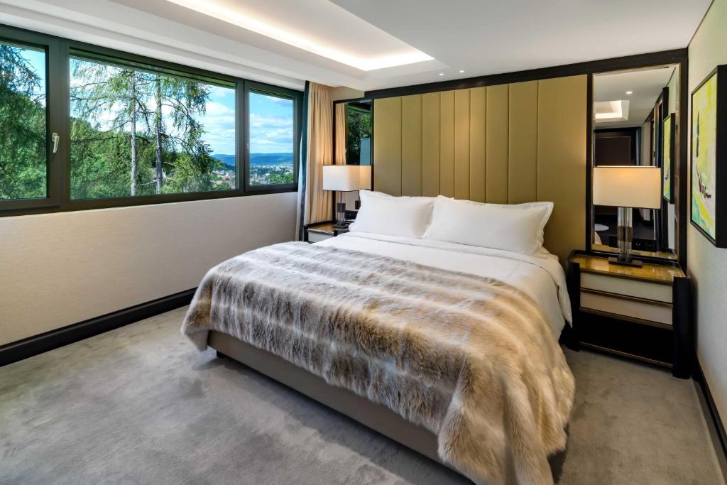 a bedroom with a large bed and large windows at FIVE Zurich - Luxury City Resort in Zürich