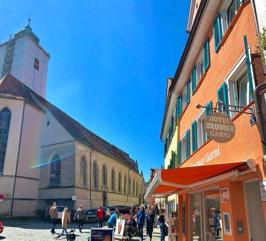 a group of people walking down a street next to a church at Hotel Garni Brugger in Lindau