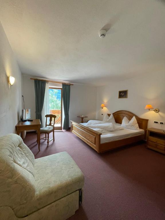 una habitación de hotel con 2 camas y una silla en Hotel Larch, en Campo di Trens