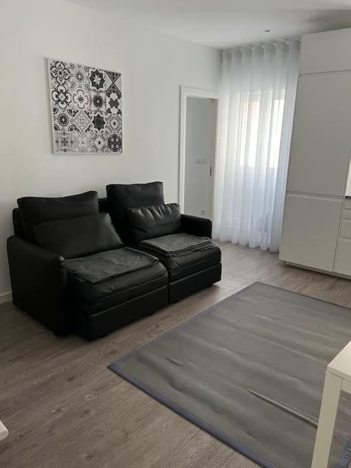 uma sala de estar com um sofá preto e um tapete em Casa Mar Azul em Nazaré