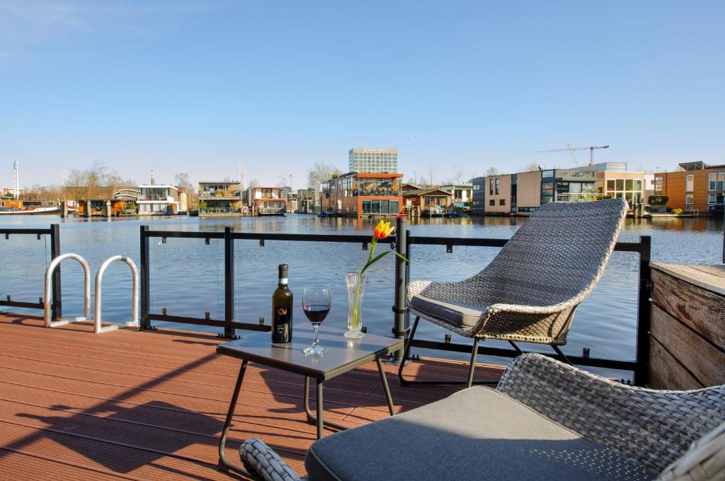 阿姆斯特丹的住宿－Houseboat studio with canalview and free bikes，天井配有两把椅子和一张桌子及一瓶葡萄酒