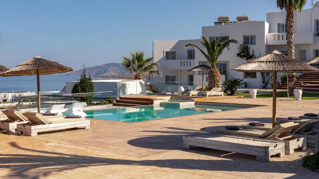 a resort with a pool and chairs and umbrellas at Arkasa Palace in Arkasa