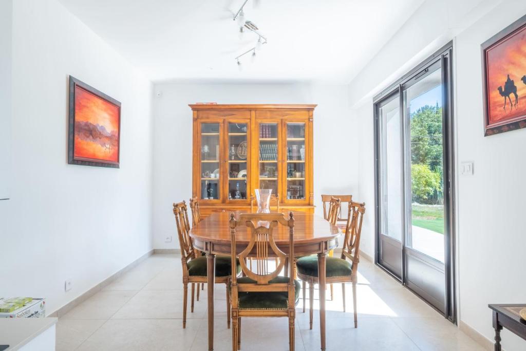 a dining room with a wooden table and chairs at SERRENDY Calm family house with swimming pool in Antibes