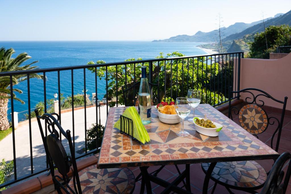 una mesa en un balcón con vistas al océano en Casa Belvedere riviera Taormina, en SantʼAlessio Siculo