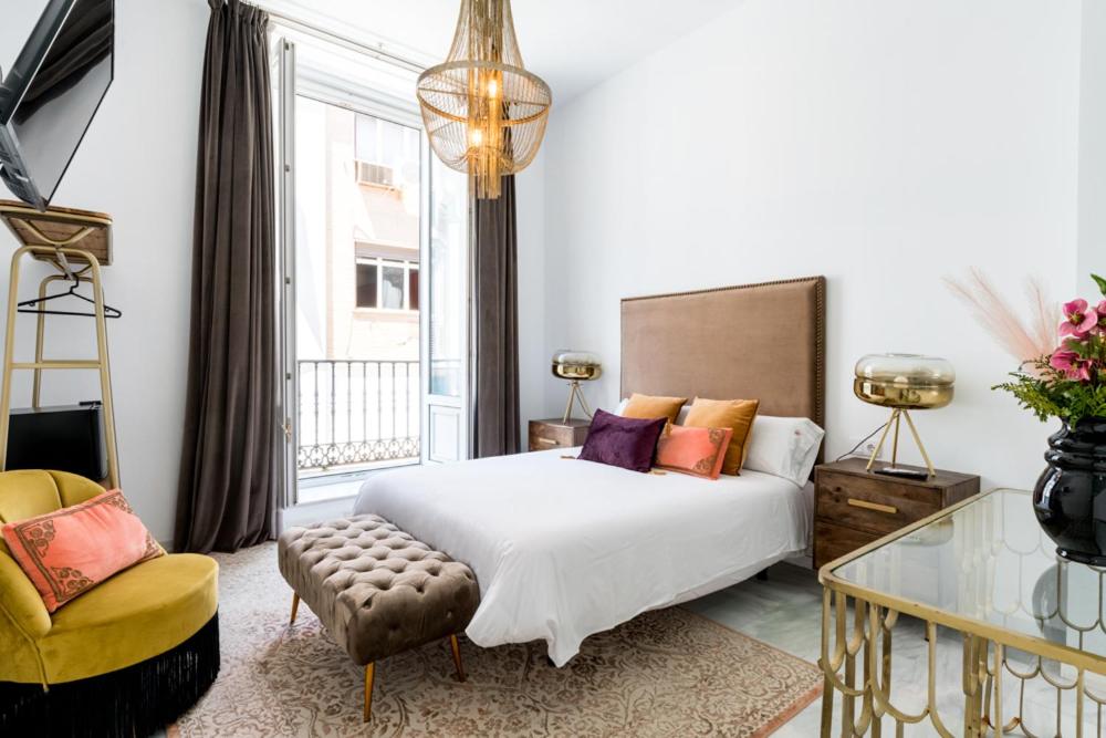 1 dormitorio con 1 cama, 1 silla y 1 ventana en Hostal Roomsole, en Sevilla