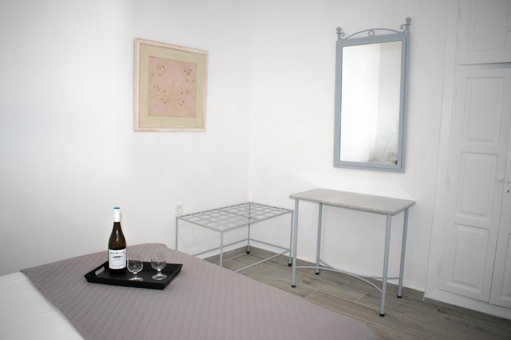 a white room with a bottle of wine and two tables at Marea Apartments in Symi