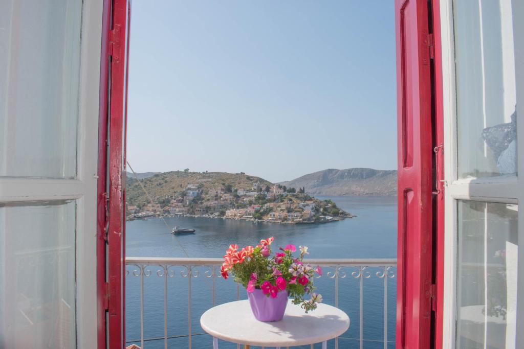 a table with a vase of flowers on a balcony at Marea Apartments in Symi