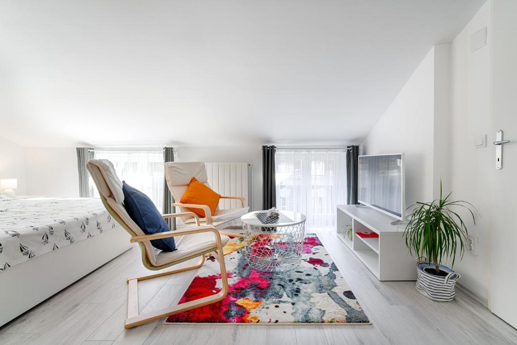 a bedroom with a bed and a chair and a rug at Sweet Loft Apartment (White) in Rijeka center in Rijeka